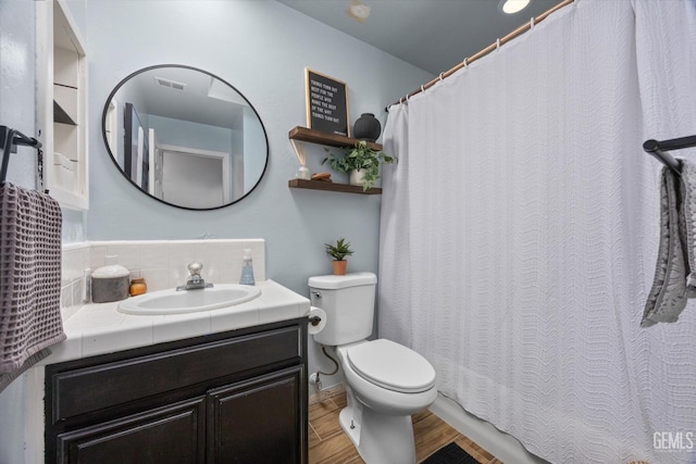 bathroom featuring visible vents, toilet, wood finished floors, vanity, and backsplash