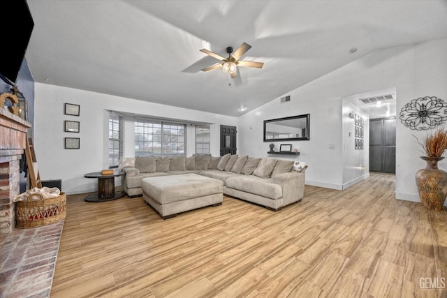 living area featuring vaulted ceiling, a fireplace, visible vents, and light wood-style floors