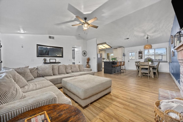 living room with lofted ceiling, ceiling fan, light wood finished floors, and visible vents