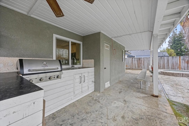 view of patio / terrace with exterior kitchen, grilling area, a sink, and fence