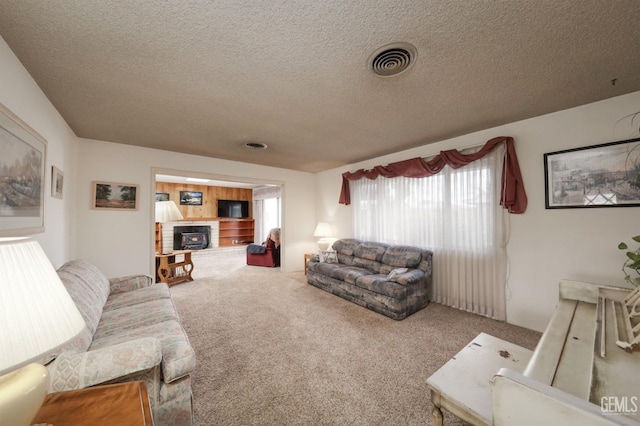 carpeted living room featuring visible vents, a fireplace with raised hearth, and a textured ceiling