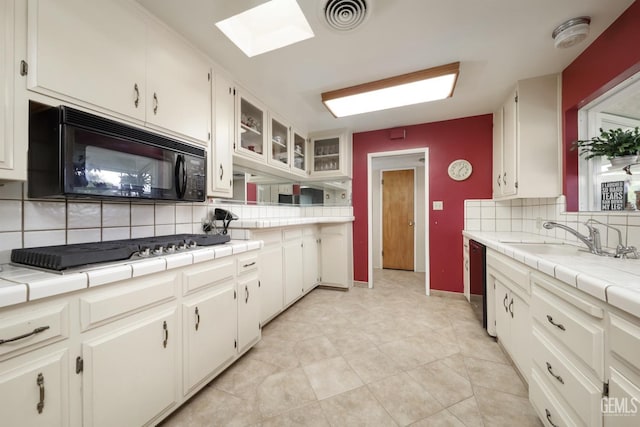 kitchen featuring a sink, white cabinetry, visible vents, decorative backsplash, and black appliances