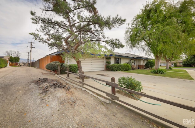 view of front of home with driveway, a garage, fence, and stucco siding