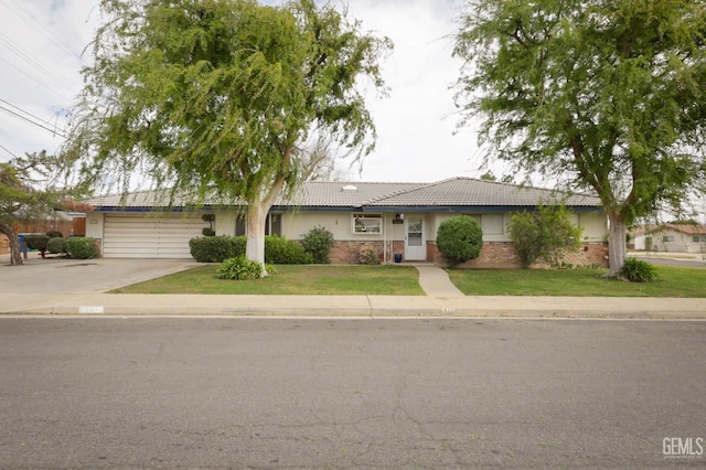 ranch-style house with a garage, a tile roof, driveway, stucco siding, and a front lawn