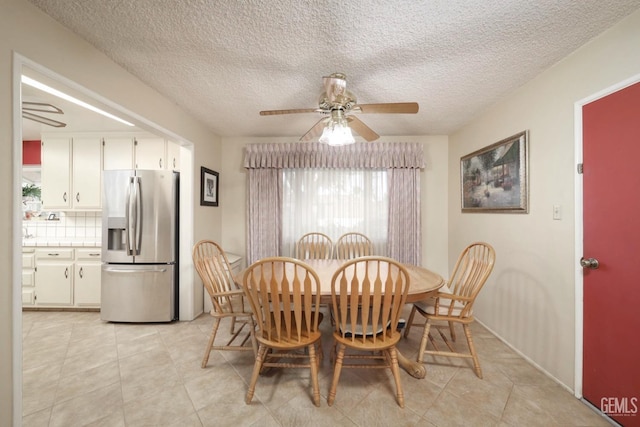 dining space with light tile patterned floors, a textured ceiling, and a ceiling fan