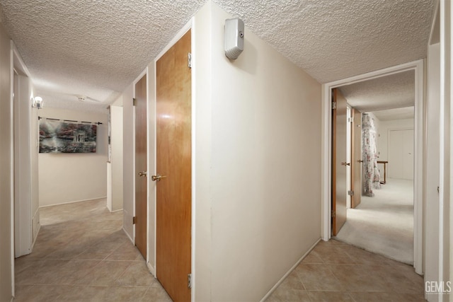 hall with light tile patterned floors and a textured ceiling