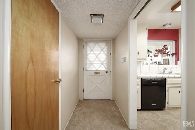 doorway featuring a sink, baseboards, a textured ceiling, and light tile patterned flooring