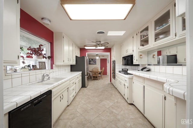 kitchen featuring tasteful backsplash, visible vents, white cabinets, tile countertops, and black appliances