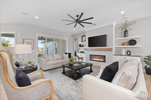 living room featuring built in shelves, ceiling fan, and light hardwood / wood-style floors