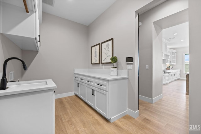 clothes washing area featuring sink and light wood-type flooring