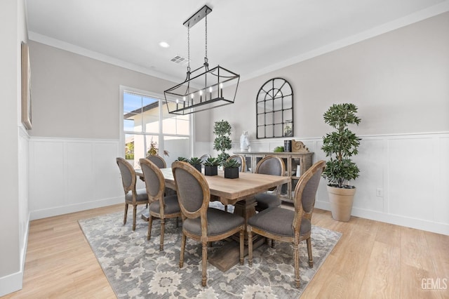 dining room featuring light hardwood / wood-style floors, ornamental molding, and a chandelier