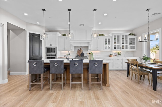 kitchen with white cabinets, decorative light fixtures, and a large island