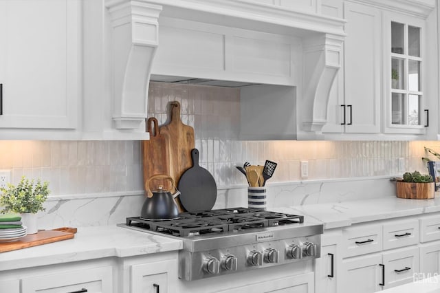 kitchen with light stone countertops, white cabinetry, stainless steel gas cooktop, and tasteful backsplash