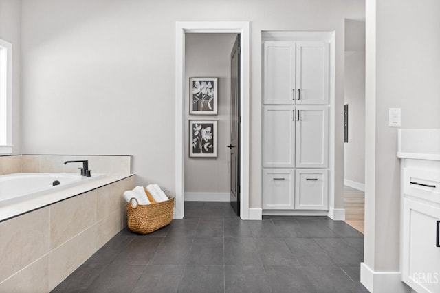 bathroom featuring tile patterned floors and a relaxing tiled tub