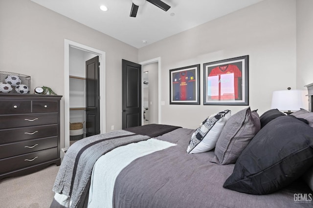 bedroom featuring ceiling fan, a walk in closet, and light carpet