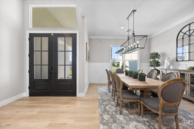 dining area featuring a chandelier, ornamental molding, light hardwood / wood-style flooring, and french doors