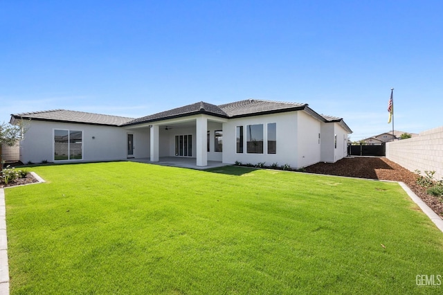 back of property with a lawn, ceiling fan, and a patio