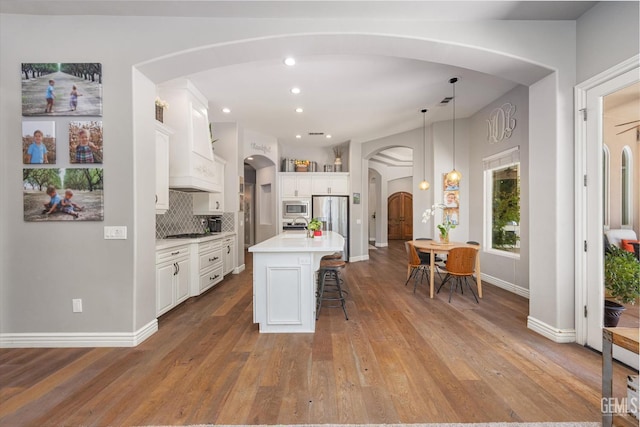 1001 Paxton Way, Bakersfield, CA 93312 - kitchen featuring arched walkways, appliances with stainless steel finishes, custom range hood, a breakfast bar area, and light countertops