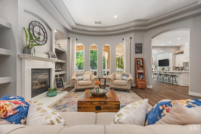 1001 Paxton Way, Bakersfield, CA 93312 - living area with wood finished floors, a glass covered fireplace, recessed lighting, built in shelves, and arched walkways