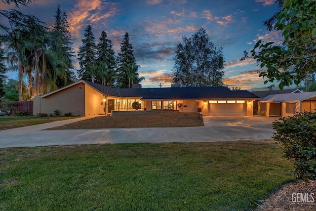 ranch-style home featuring fence, a yard, stucco siding, an attached garage, and concrete driveway