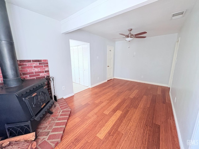 2711 Hubbard St, Bakersfield, CA 93301 - unfurnished living room featuring a wood stove, a ceiling fan, wood finished floors, and baseboards