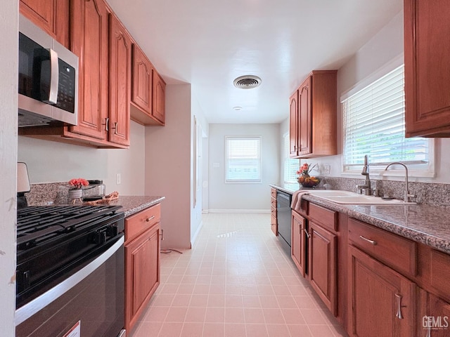 2711 Hubbard St, Bakersfield, CA 93301 - kitchen featuring gas stove, a sink, stainless steel microwave, and brown cabinetry