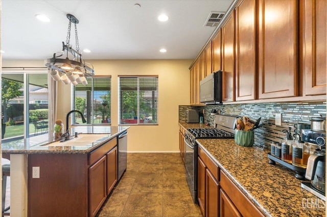 16018 La Strada Ct, Bakersfield, CA 93314 - kitchen with appliances with stainless steel finishes, brown cabinetry, backsplash, a center island with sink, and recessed lighting