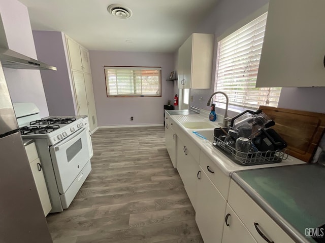 3914 Apache Ave, Bakersfield, CA 93309 - kitchen featuring gas range gas stove, exhaust hood, light wood-style floors, white cabinetry, and light countertops