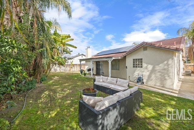 rear view of house with a patio, an outdoor hangout area, solar panels, a yard, and stucco siding