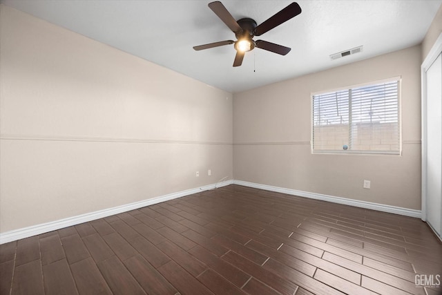 spare room with dark wood-style floors, visible vents, baseboards, and a ceiling fan