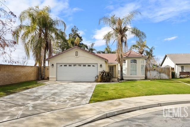 view of front of house featuring concrete driveway, stucco siding, an attached garage, fence, and a front yard