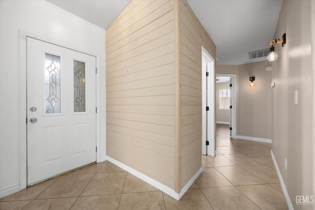 entrance foyer with light tile patterned floors, wood walls, and visible vents