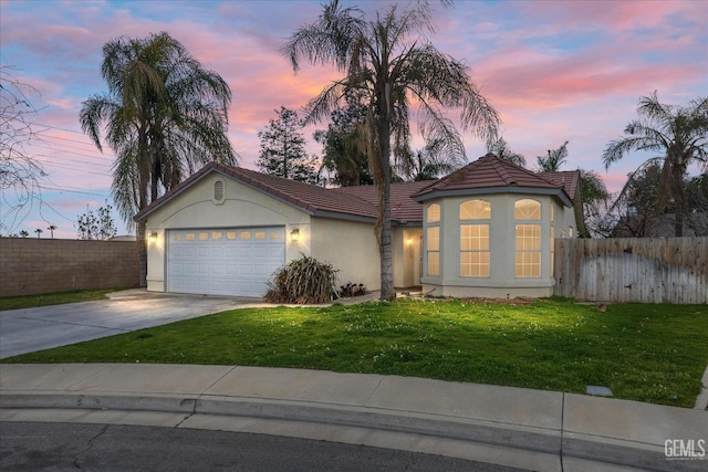 mediterranean / spanish home with driveway, a front lawn, fence, and stucco siding