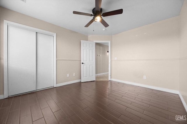 unfurnished bedroom featuring dark wood-style floors, ceiling fan, a closet, and baseboards