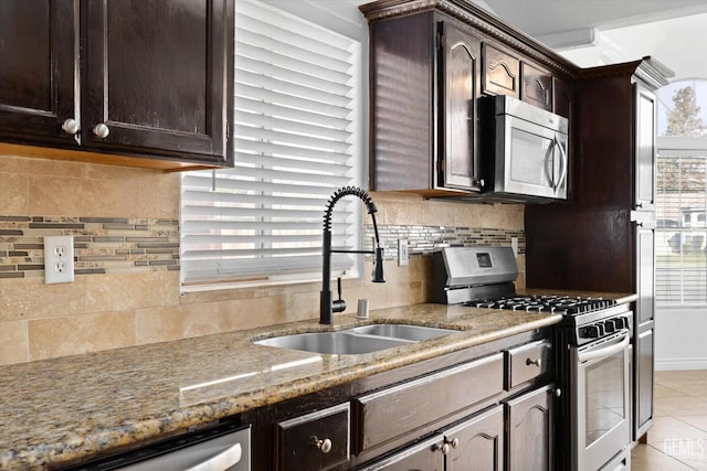 kitchen with light tile patterned floors, stainless steel appliances, dark brown cabinets, and a sink