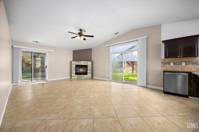 unfurnished living room with light tile patterned floors, lofted ceiling, visible vents, a ceiling fan, and a glass covered fireplace