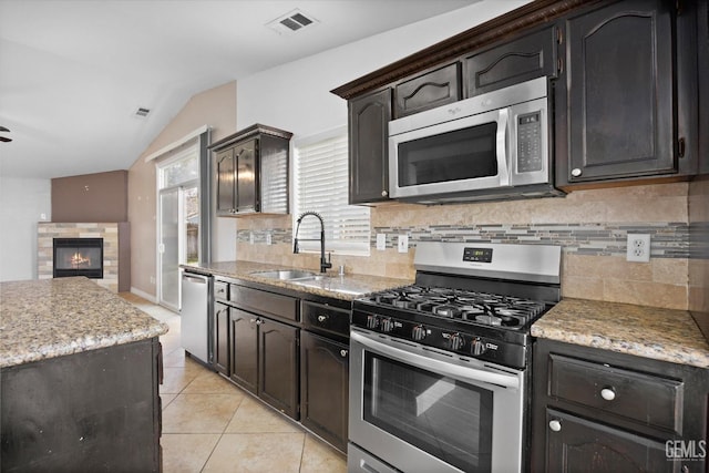 kitchen with visible vents, decorative backsplash, a tiled fireplace, appliances with stainless steel finishes, and a sink