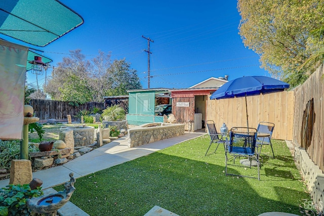 view of yard featuring an outbuilding, an outdoor fire pit, and a fenced backyard