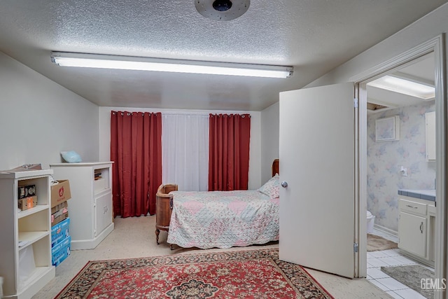 bedroom featuring connected bathroom, wallpapered walls, and a textured ceiling