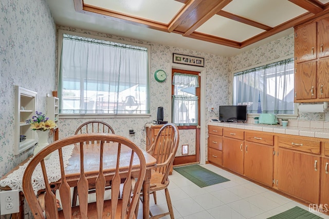 kitchen with tile counters, light tile patterned flooring, and wallpapered walls