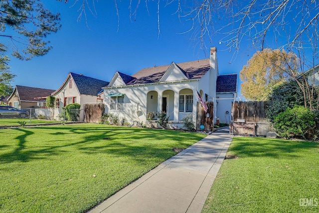 view of front of property featuring a front lawn, fence, and stucco siding