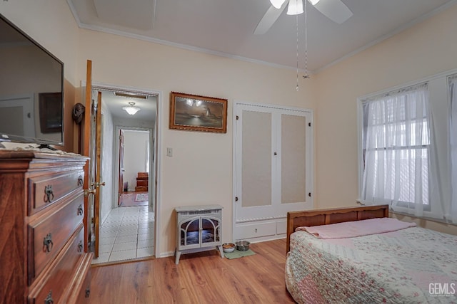 bedroom featuring ceiling fan, crown molding, and light wood-style floors