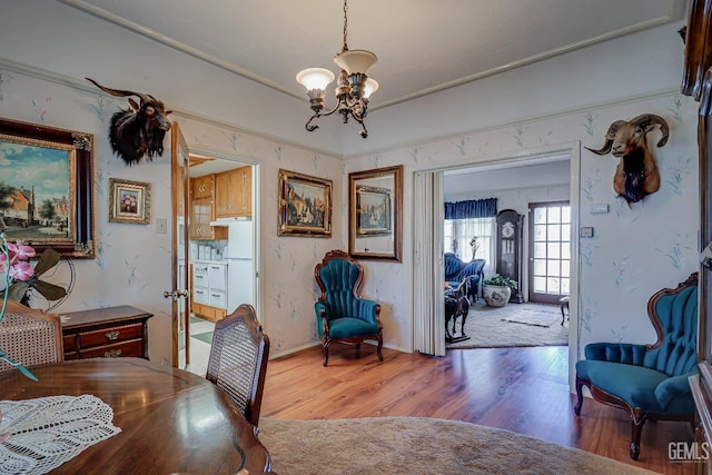 dining area featuring a notable chandelier, wood finished floors, and wallpapered walls