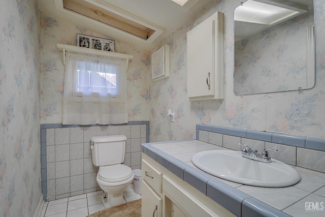 bathroom featuring toilet, wainscoting, tile patterned flooring, and wallpapered walls