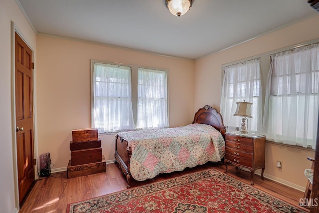 bedroom featuring baseboards, wood finished floors, and ornamental molding