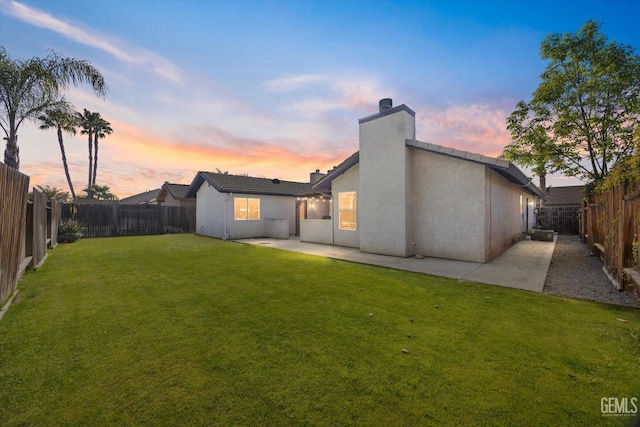 back of house with a yard, a fenced backyard, a patio, and stucco siding