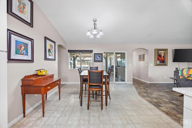 dining room with arched walkways, vaulted ceiling, a chandelier, and baseboards