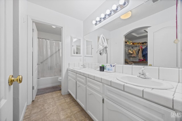 full bathroom with double vanity, shower / tub combo, a sink, and toilet