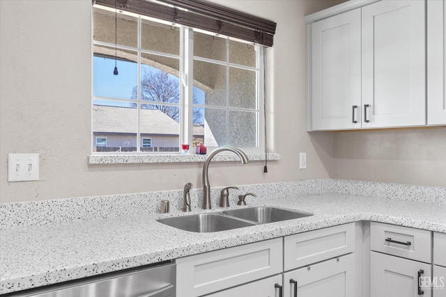 kitchen featuring a sink, light stone countertops, white cabinets, and dishwasher