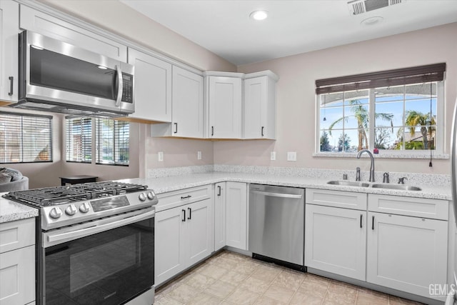 kitchen with visible vents, stainless steel appliances, white cabinetry, a sink, and recessed lighting